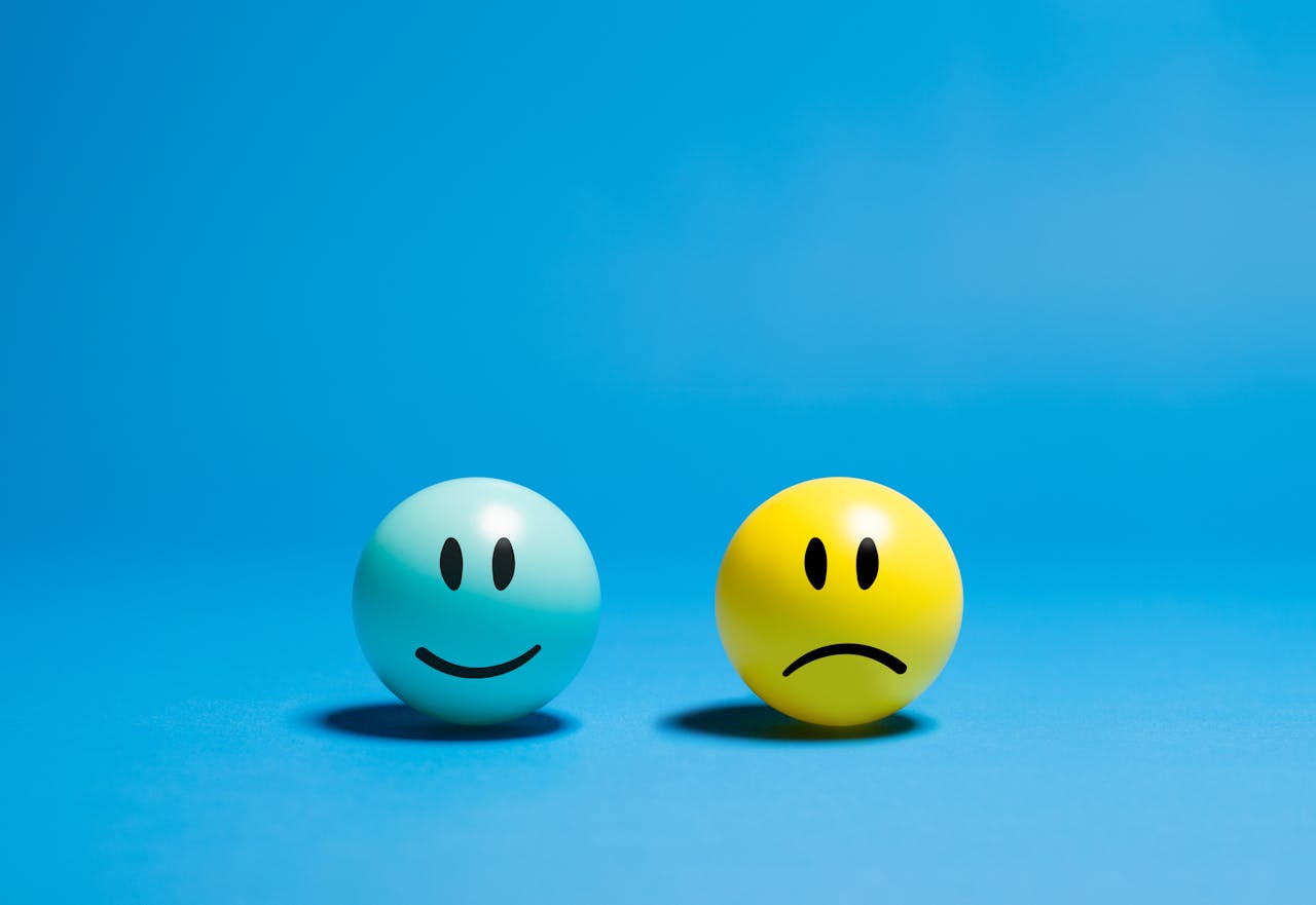 Two smiley balls representing opposite emotions on a blue background.